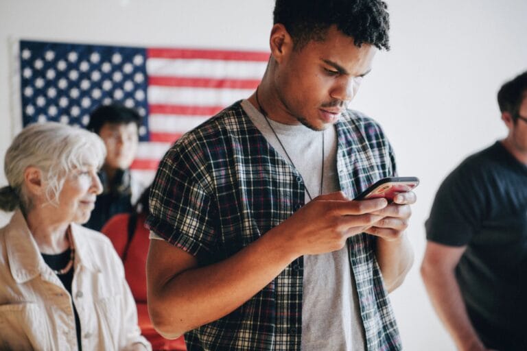 Young man intently using a smartphone with an American flag backdrop, representing U.S. citizens engaging with political communications. Essential for campaigns, PACs, and security firms in the United States combating voter fraud text scams, political donation fraud, and SMS phishing in fundraising. Checktxt offers robust solutions for secure political fundraising and verifying SMS communication authenticity. #Checktxt #PoliticalDonations #VoterFraud #TextScams #PoliticalFundraising #SMSVerification #USPolitics #CampaignSecurity #Cybersecurity #UnitedStates #MobileSecurity
