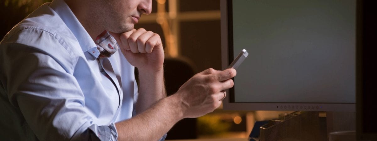 Man focused on smartphone, reviewing text messages or data in an office setting. Relevant for enterprises, MSSPs, developers, and product managers in the United States seeking advanced SMS verification and text analysis solutions. Discover Checktxt for secure mobile communication and compliance. #Checktxt #SMSVerification #EnterpriseSolutions #MobileSecurity #TextAnalysis #MSSP #Developers #ProductManagement #CustomerSupport #UnitedStates